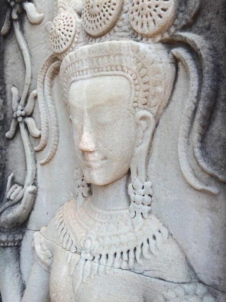 Stone carving depicting a serene figure with intricate headgear and jewelry, showcasing craftsmanship.