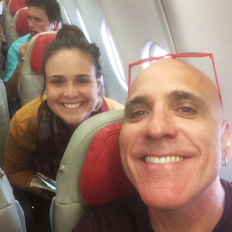 Inner Space host, Ralph Williams, sits on a plane with his daughter directly behind him, posing for a selfie as they wait to depart for Kathmandu, Nepal.