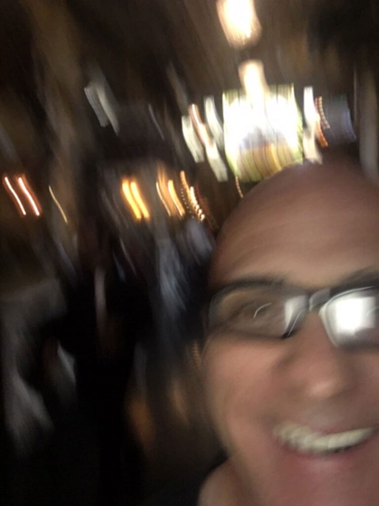 Blurry close-up of a person's face with an indistinct, dimly lit indoor background.