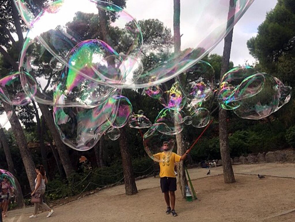 A park entertainer waves his magic wand and releases an aerial stampede of giant bubbles across Park Güell in Barcelona, Spain.