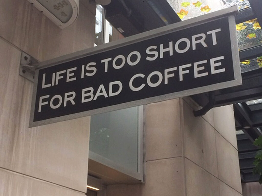 Sign on a building stating "Life is too short for bad coffee" in white on a black background.