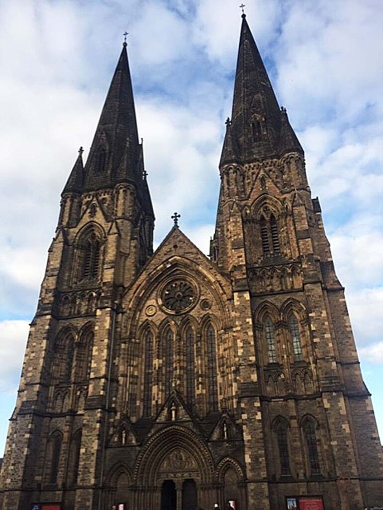 Large stone Gothic cathedral with twin spires, intricate carvings, and central rose window.