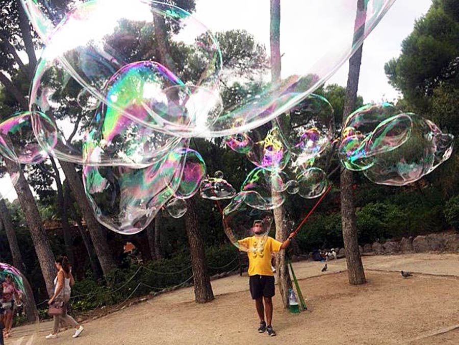 A park entertainer releases a big batch of giant bubbles across Park Güell in Barcelona, Spain.