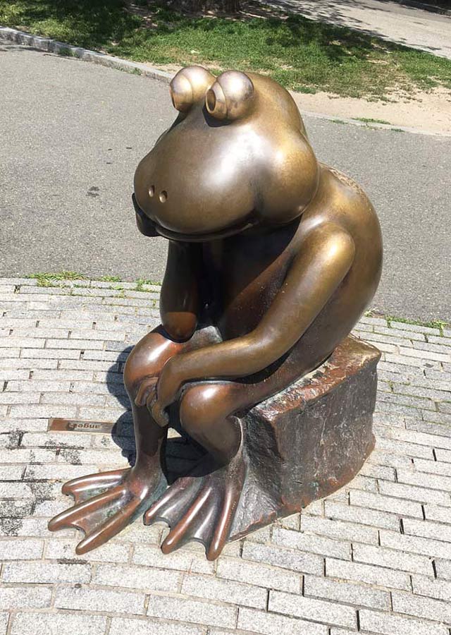 Bronze sculpture in Boston Public Garden of a large bug-eye frog sitting on a rock and thinking.