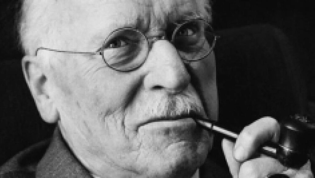 Black & white portrait-photo (historical) of Swiss psychologist, Carl Jung, smoking a pipe.