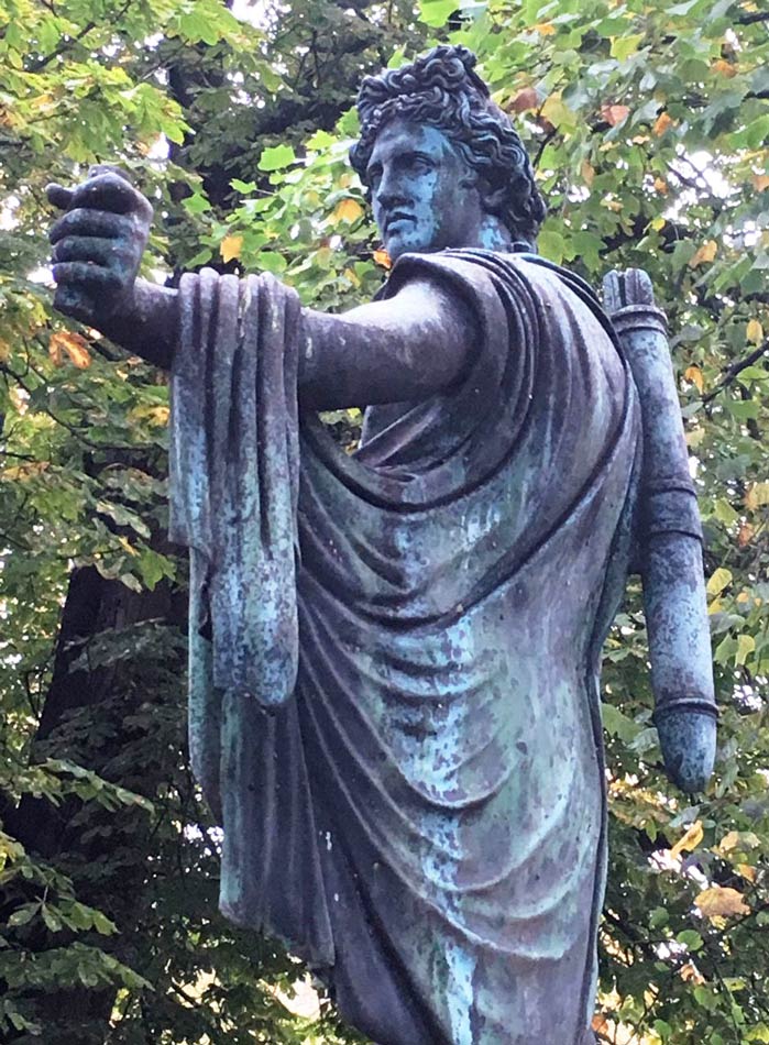 Metal bluish sculpture in Ørsteds Park in Copenhagen of a male archer drawing his bow.