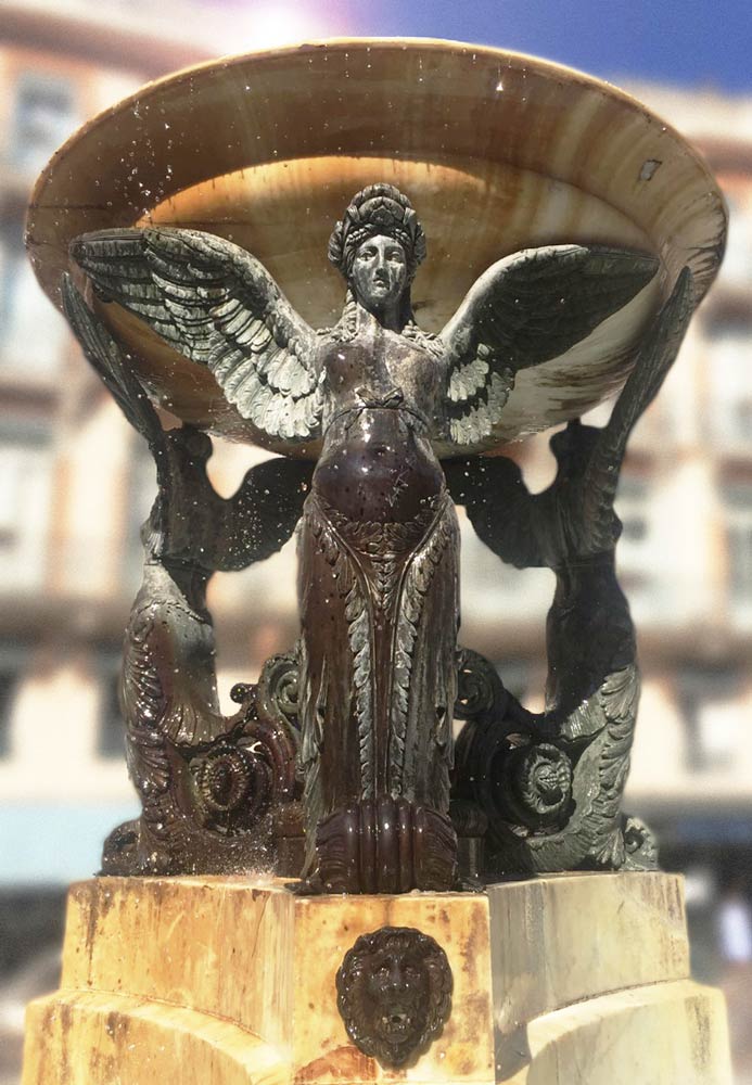 A stoic female angel cast in bronze supports a large fountain bowl with her outstretched wings in Geneva, Switzerland.