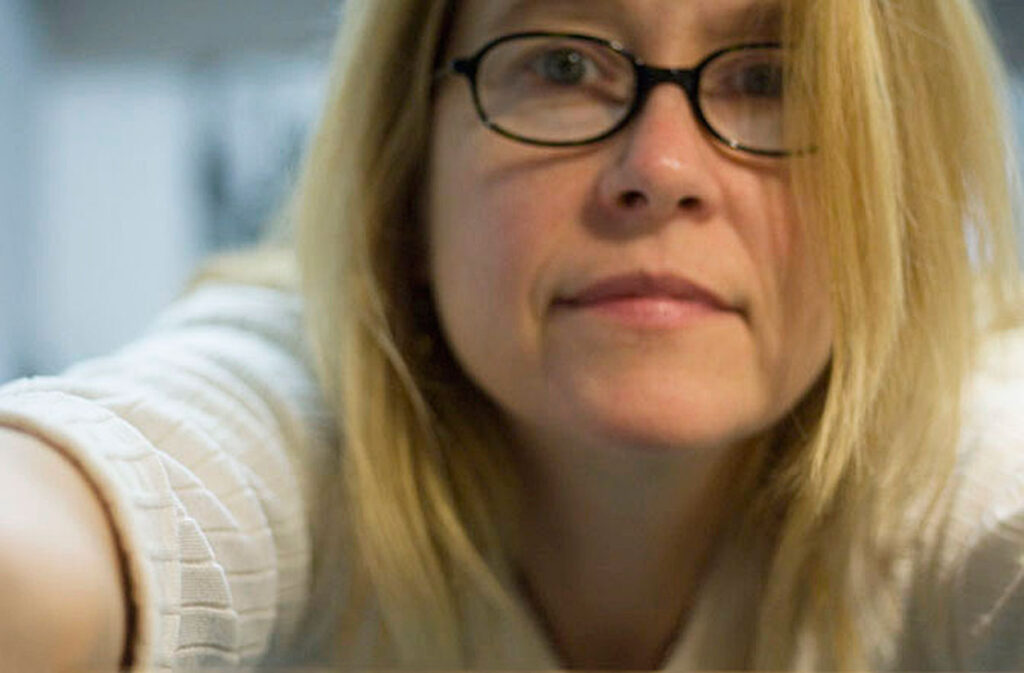 Self-portrait of photographer, Grace McEvoy, wearing brown-rimmed glasses with her sandy-blonde hair falling around her face.