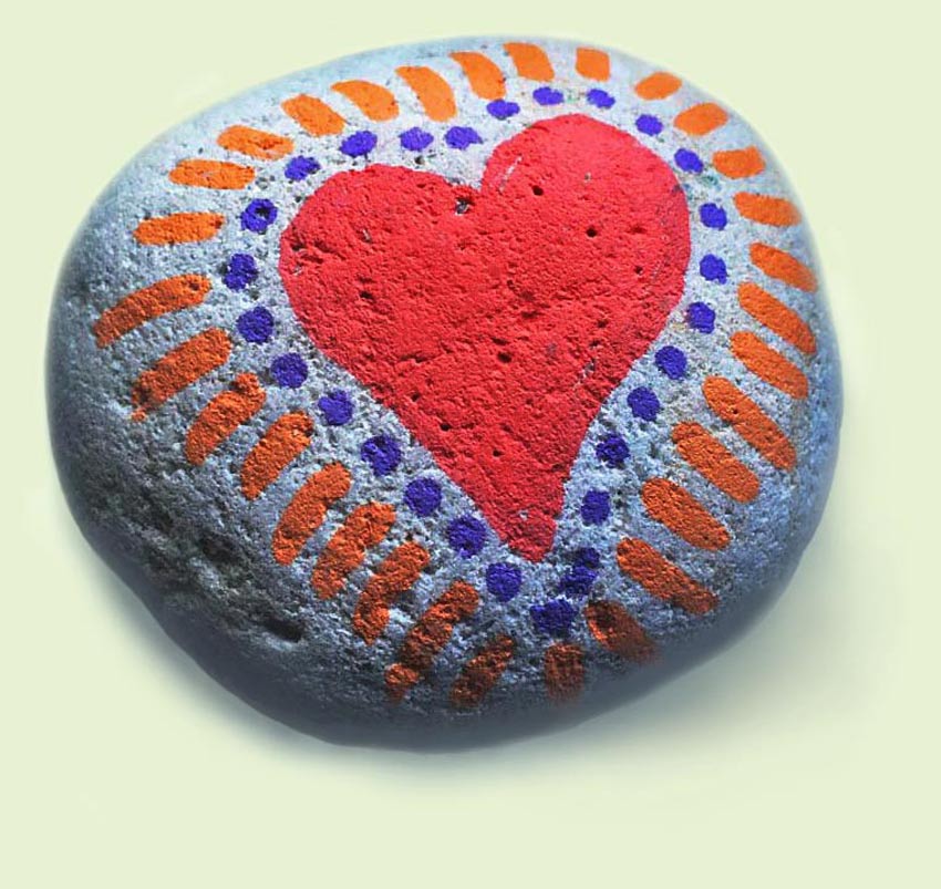 A big ed heart with orange rays hand-painted onto porous stone.