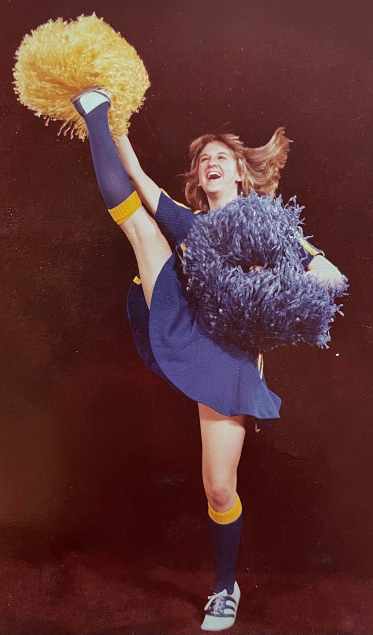 Cheerleading portrait (Jr. High) of Dana Brock kicking one leg high while holding pom-poms.