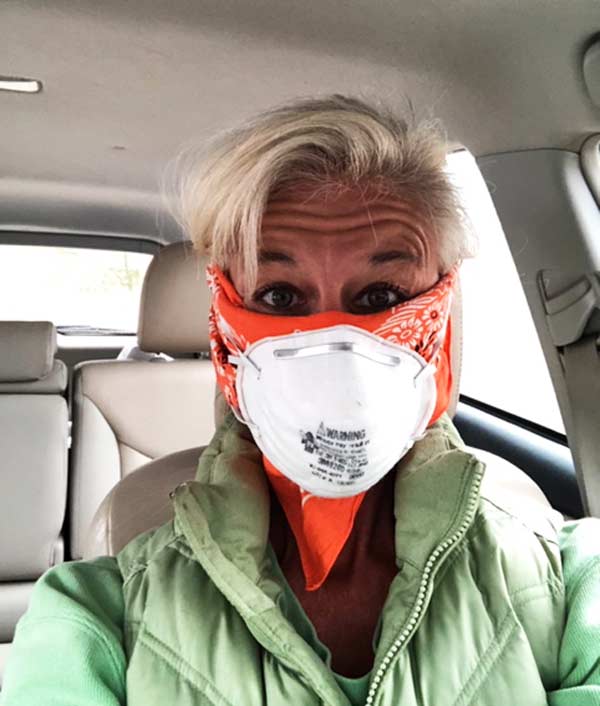 Selfie of Dana Brock wearing a dust mask over an orange bandana while driving during the Covid crisis in 2020.