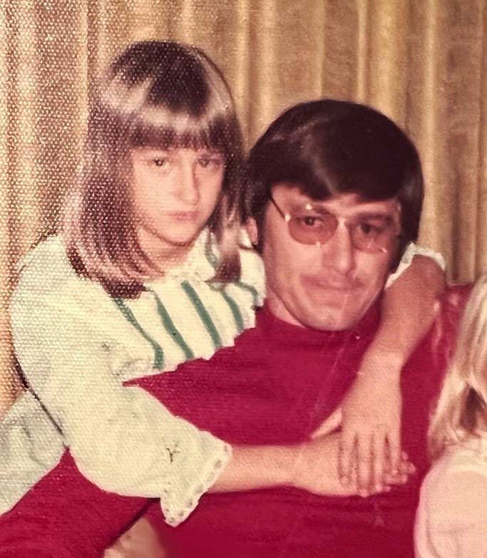 Dana Brock, age 10, sits behind her father with her arms around him.