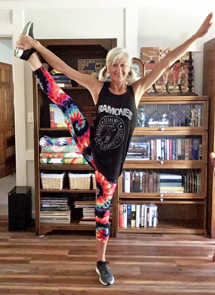 Dana Brock exercises at home, balancing on one leg as her arms and free leg extend upwards.