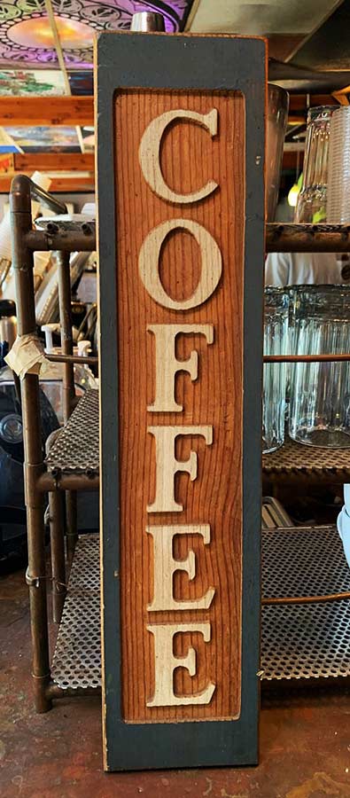 A long wooden plaque with the word COFFEE etched into it.