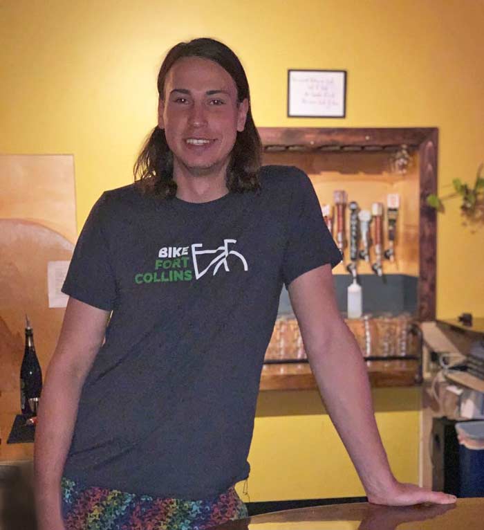 Connor Williams, co-owner of THE ATRIUM Bar & Lounge in Fort Collins, CO, smiles while leaning on the bar.