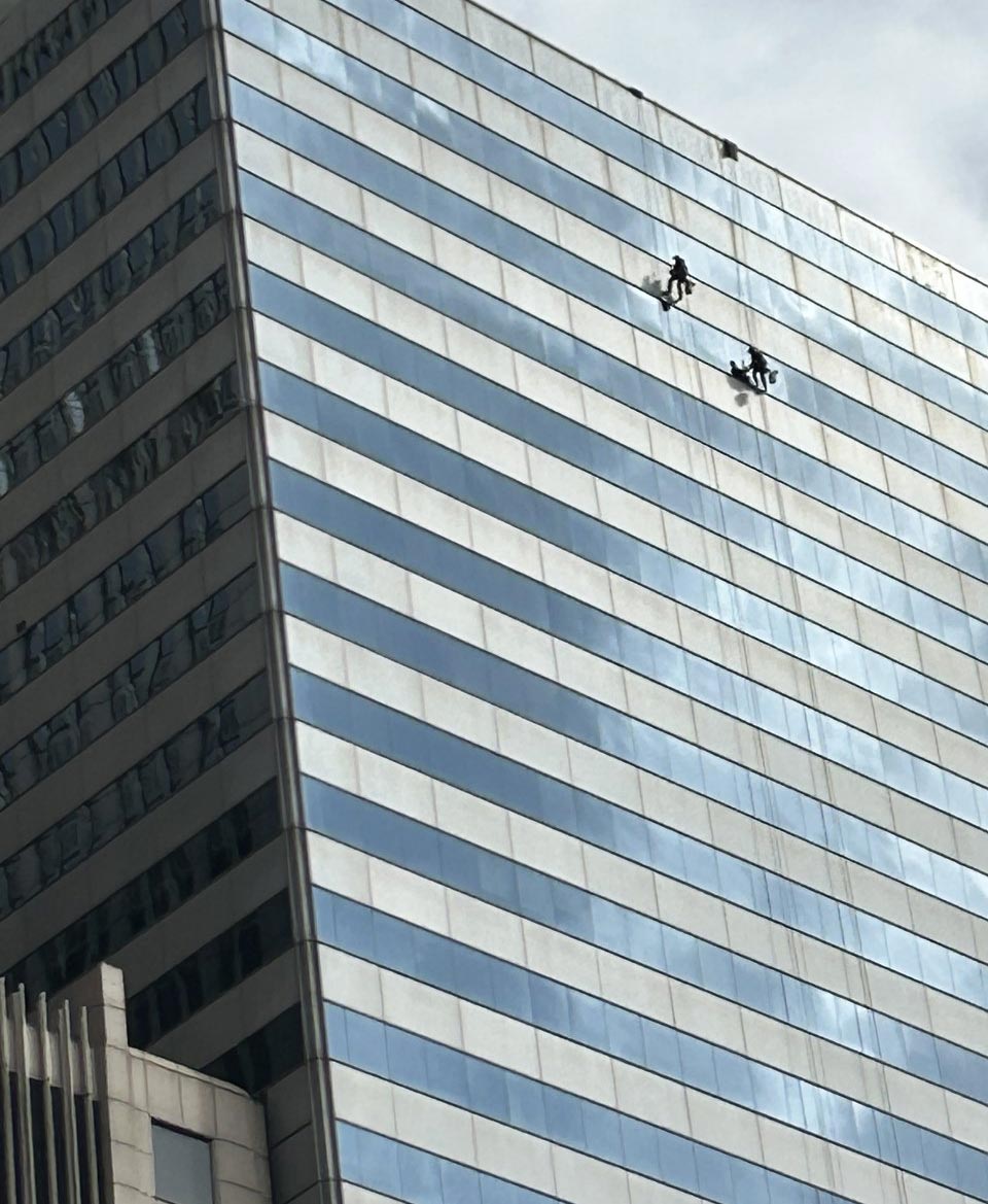 Looking up at two window washers working near the top of the USG Building in Chicago.