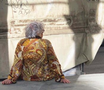 ITALIAN STYLE! An older woman in a colorful jacket rests on a concrete ledge in Florence, Italy.