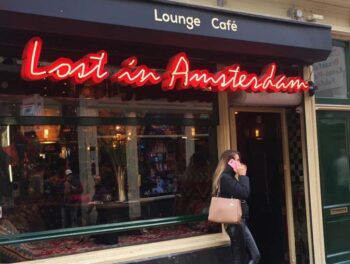 A young woman appears to be making an urgent call while standing outside the Lost In Amsterdam Cafe in central Amsterdam, Netherlands. Do you suppose she's actually lost in Amsterdam?