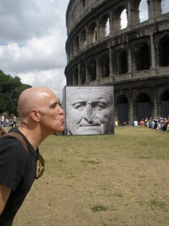 Posing outside the Roman Colosseum—I'm pretending to kiss the cheek of an old man with a crumbly nose, when actually I've just positioned myself in front a giant poster for a "relics exhibit" that's off in the distance.