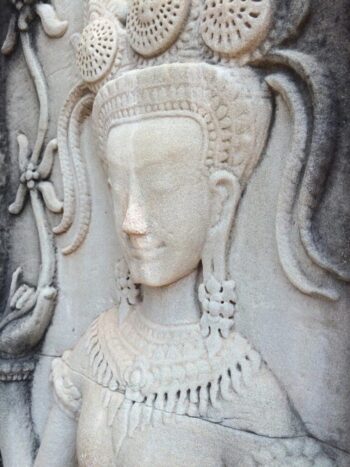 This female form was carved into a stone pillar. Notice the elaborate headpiece, decorative draping across the chest, oversized earrings with stretched lobes, and the elongated and flowering index finger.